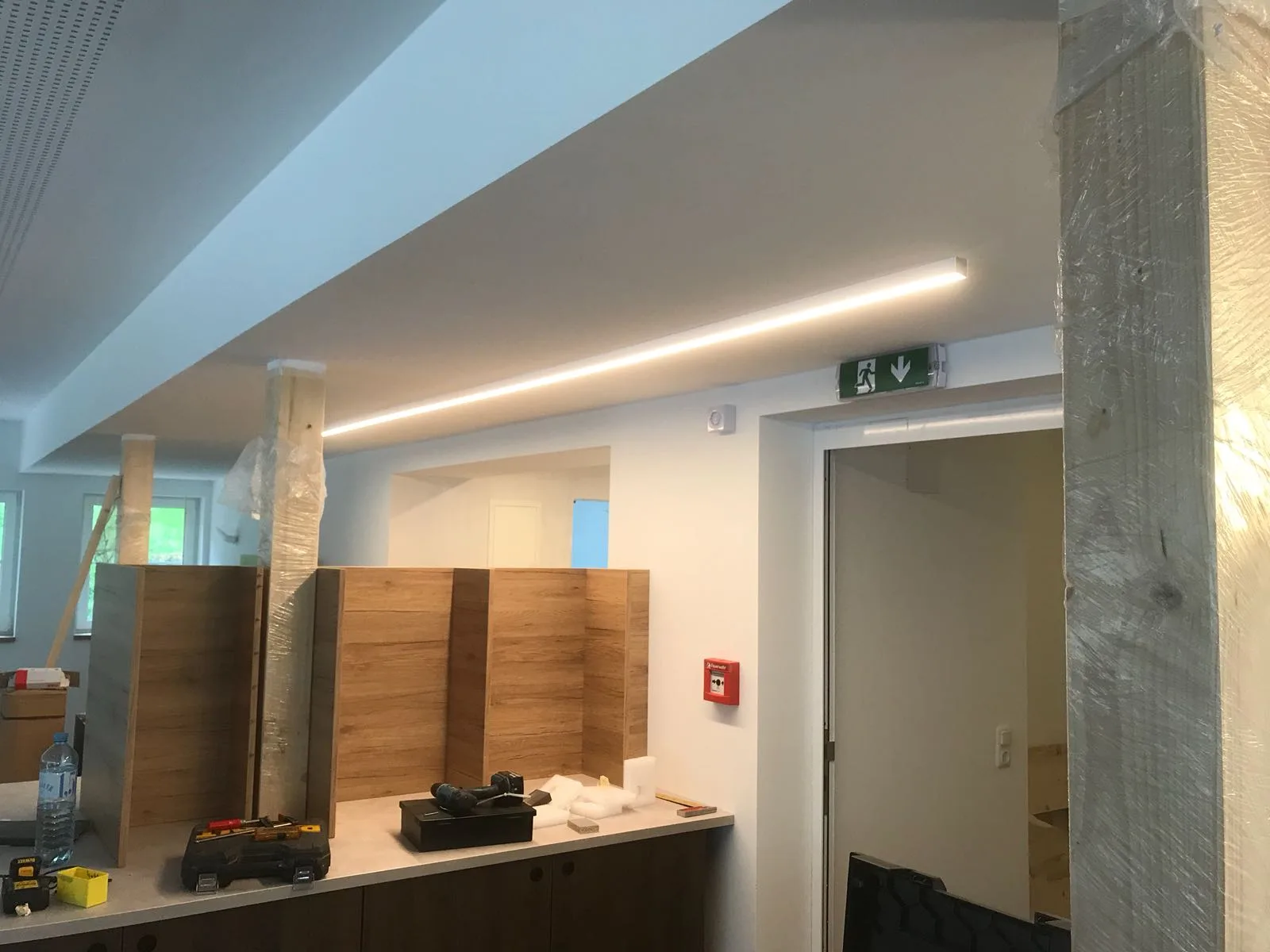 Durchgehendes Lichtband an einer abgehängten Decke, darunter ein Raum im Ausbau